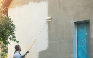 house painter painting building exterior with roller - anti-graffiti coatings
